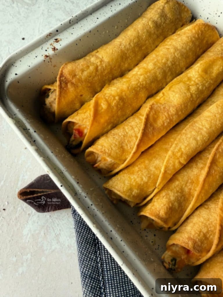 Close-up of taquitos baking in the oven, starting to brown