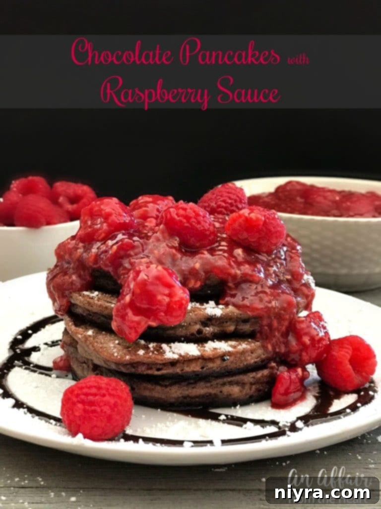 Plate of chocolate pancakes with a generous pour of raspberry sauce
