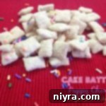 Cake batter puppy chow on a red surface with text 