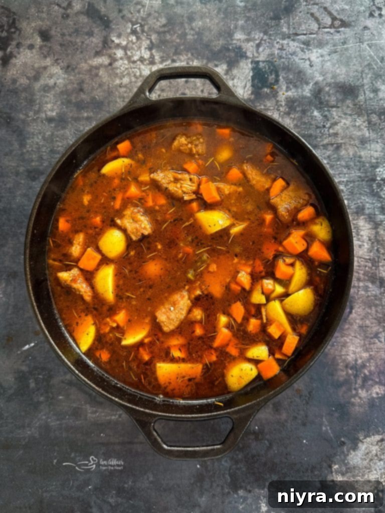 Pork stew simmering with carrots and potatoes.