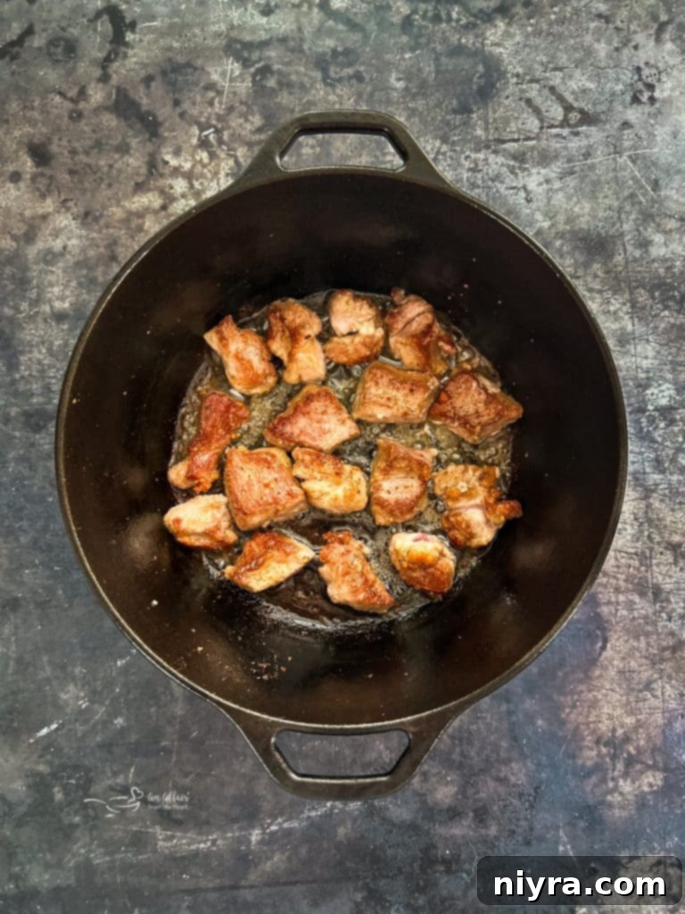 Searing flour-coated pork in a Dutch oven.