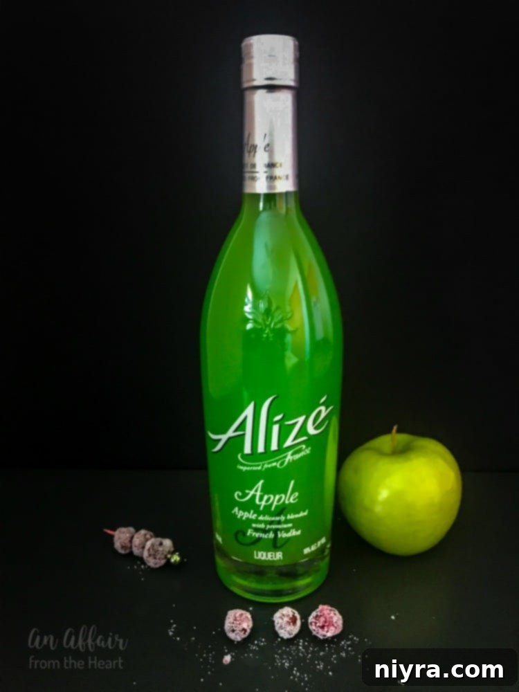 CranApple Fizz Cocktail beside a bottle of Alizé Apple liqueur, highlighting the key ingredient.