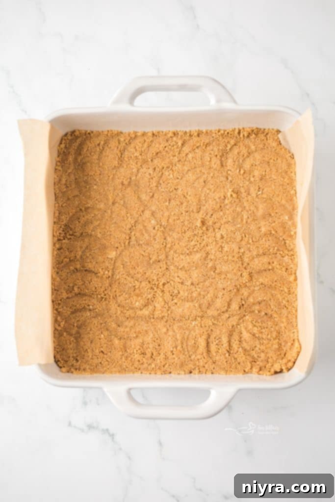 Zesty Key Lime Pie Bars 8 Graham cracker crust being pressed into an 8x8 inch baking pan, ready for the filling.