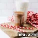 Homemade Copycat Nesquik Recipe 14 A Mason jar of Homemade Nesquik with a tall glass of milk behind it.