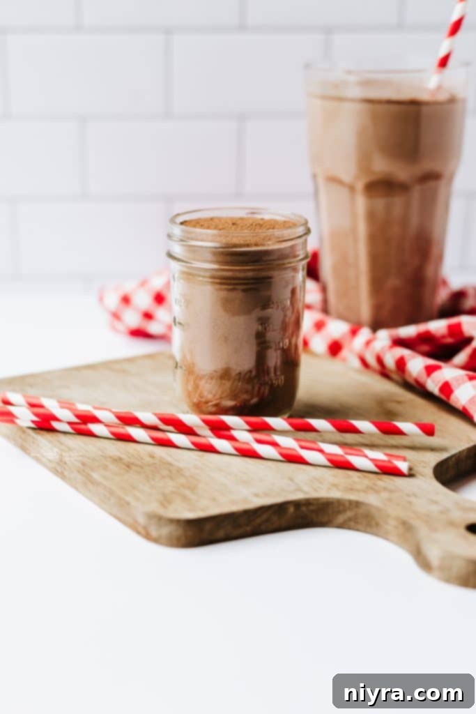 Homemade Copycat Nesquik Recipe 7 A person pouring the freshly sifted homemade chocolate milk powder into a mason jar for storage.