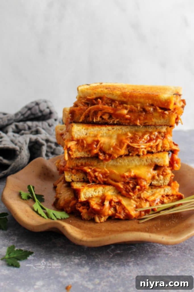 A perfectly grilled BBQ Pulled Pork Grilled Cheese sandwich, cut in half, revealing gooey melted cheese and tender pork.