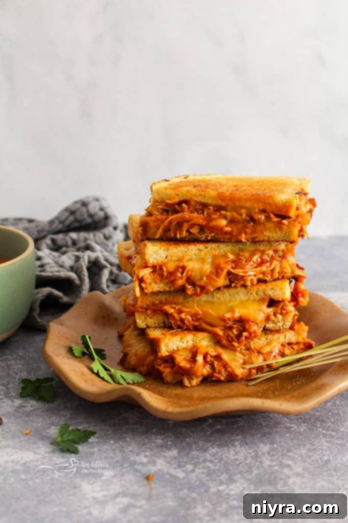 A close-up shot of the savory pulled pork filling and melted cheese inside a grilled cheese sandwich.