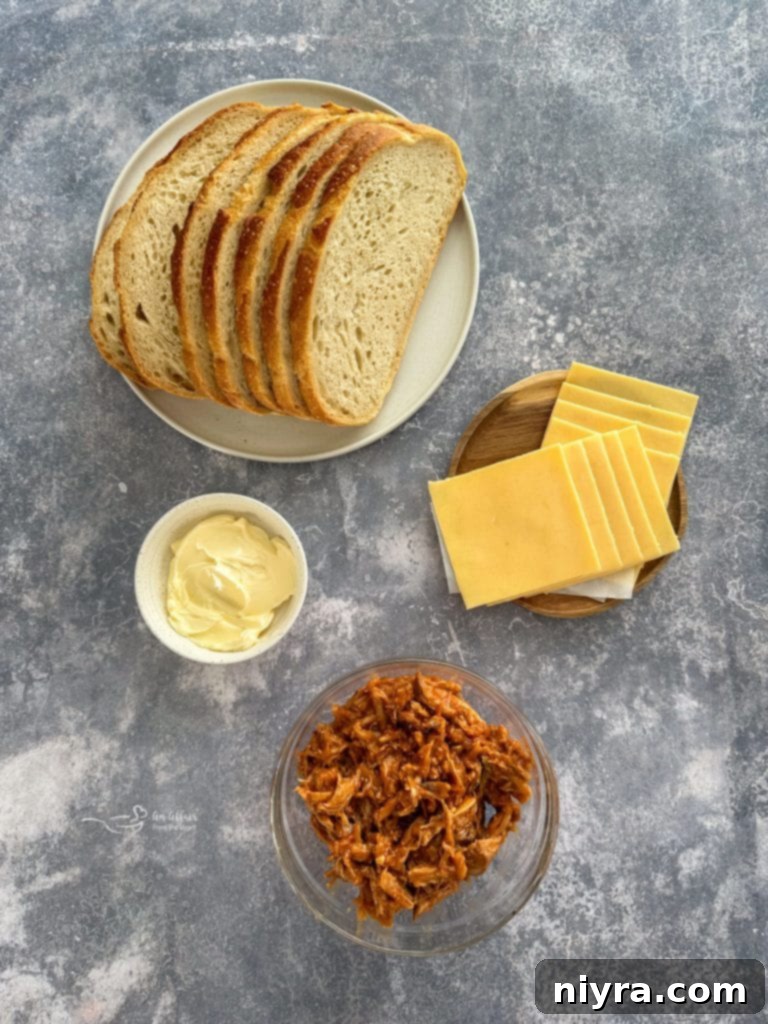 Two Dr. Pepper BBQ Pulled Pork Grilled Cheese sandwiches served on a white plate, with a side of extra BBQ sauce.