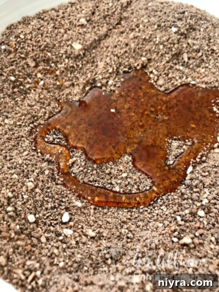 A stream of raw honey being poured onto the rum ball mixture, acting as a binder.