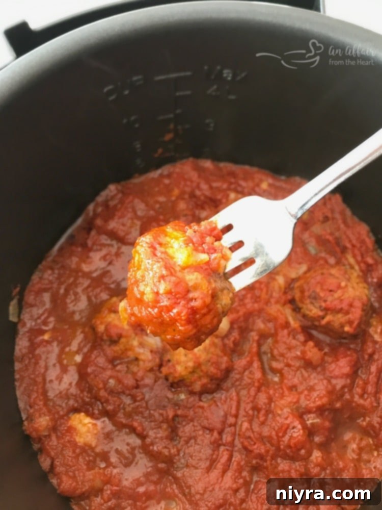 Perfectly cooked meatballs simmering in rich marinara sauce inside an Instant Pot.