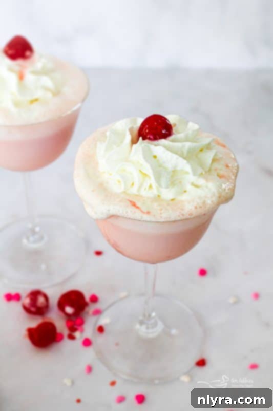 Pink Velvet Dream 14 Pink Squirrel cocktail in a glass with a cherry and whipped cream.