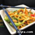 Asian Slaw in a white square bowl with chopsticks laying on top and text