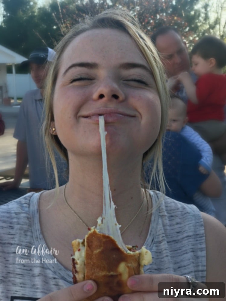 A close-up shot of a Spicy Grilled Cheese Chili Dog with an incredibly delicious cheese pull, highlighting the melted pepper jack cheese and rich texture.