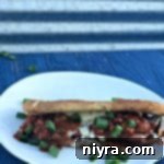 Spicy Grilled Cheese Chili Dog on a white plate, garnished and ready to be enjoyed.