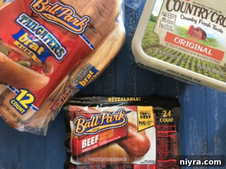 Selection of key ingredients from Sam's Club: Ball Park Beef Franks, Ball Park Tailgaters Brat Buns, Country Crock, and shredded Pepper Jack Cheese, ready for chili dog recipe.