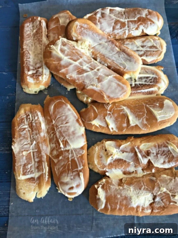 Ball Park Tailgaters Brat Buns being flattened with a rolling pin and generously spread with Country Crock, preparing them for the grill.