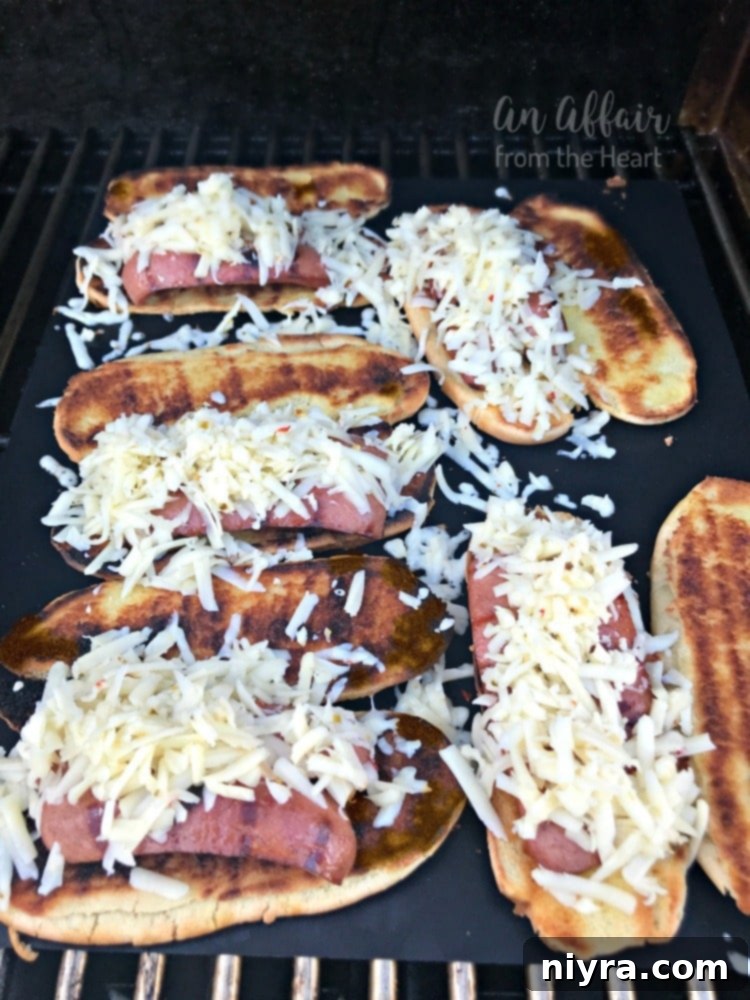 A grilled hot dog nestled onto a toasted bun, generously topped with shredded pepper jack cheese, melting beautifully on the grill.