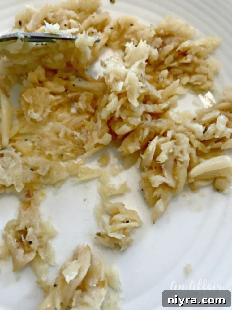 Close-up of perfectly mashed roasted garlic, soft and golden, ready to be mixed into butter