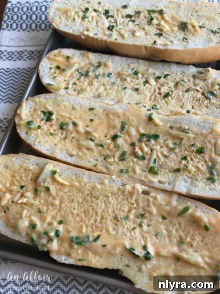 Freshly prepared roasted garlic butter spread generously on slices of crusty Italian bread, ready for baking or grilling