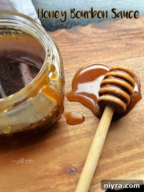 Hero shot of Honey Bourbon Sauce in a clear jug with a spoon