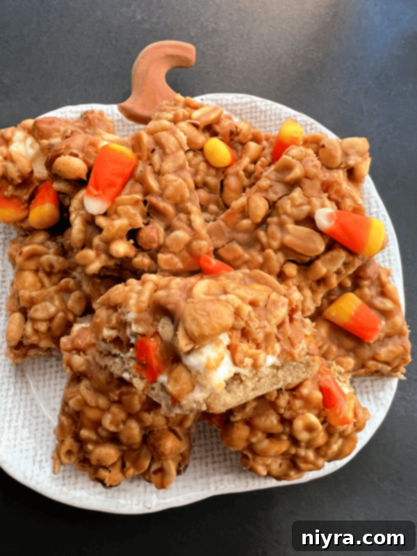 Overhead view of all the topping ingredients laid out on a table: corn syrup, butter, vanilla, peanut butter chips, Rice Krispies, peanuts, and candy corn.