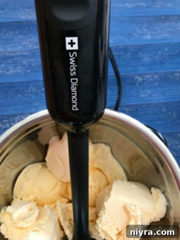 Vanilla ice cream being blended in a stainless steel bowl