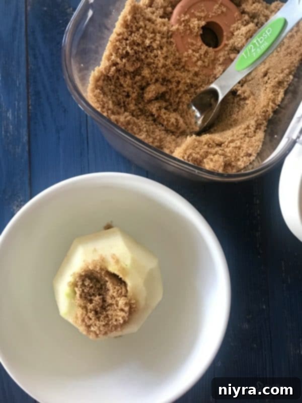 Peeled and cored apple in a bowl with brown sugar