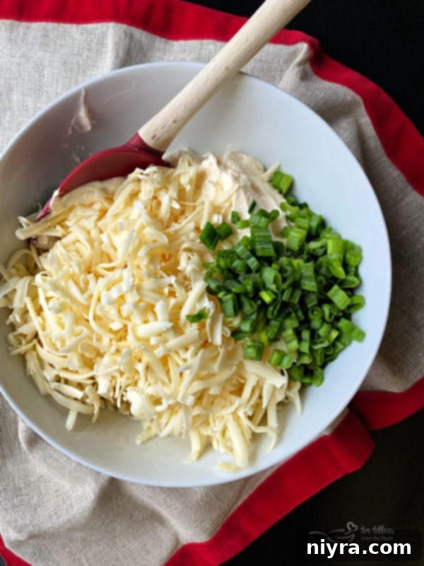 Mixing bowl with Swiss cheese, mayonnaise, and scallions