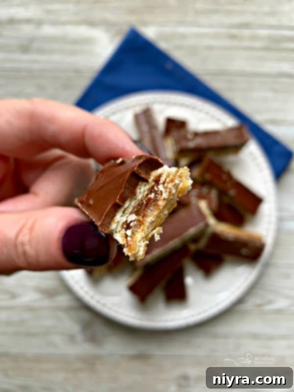 Triple Layer Chocolate Caramel Delight 13 Close-up of a homemade Twix bar, showing the crisp cracker layers, soft caramel, and smooth chocolate-peanut butter ganache.