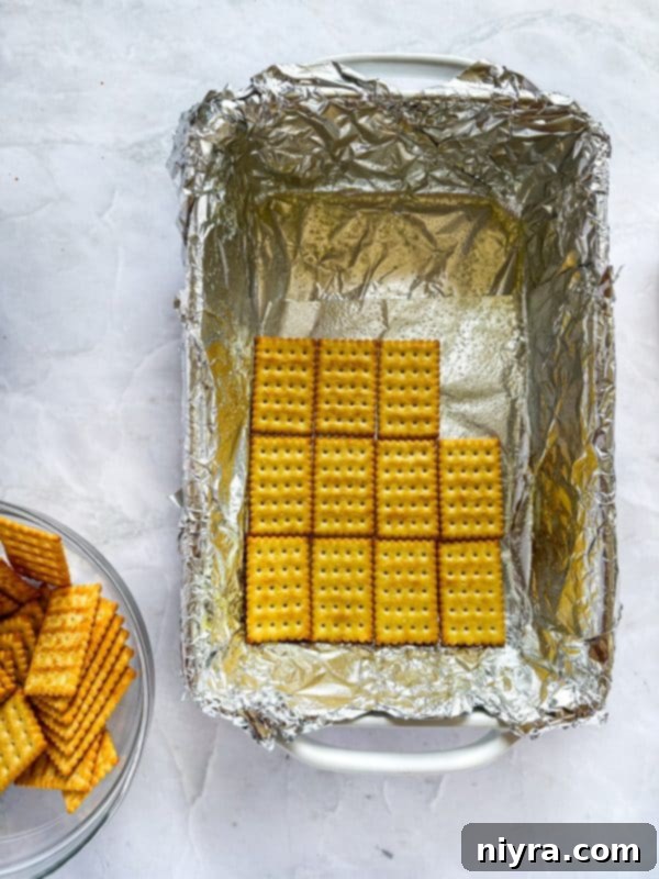 Triple Layer Chocolate Caramel Delight 5 A 9x13 inch baking dish lined with aluminum foil, ready for the cracker base.