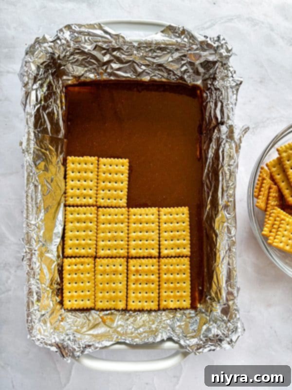 Triple Layer Chocolate Caramel Delight 7 Caramel mixture simmering in a saucepan on the stovetop, being stirred with a wooden spoon.