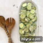 Crisp Cucumber Ranch Salad 16 Cucumber Ranch Salad on a white serving dish and wooden salad serving spoons on a light colored table.