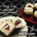 Cherry torte cupcake cut in half on a white plate and others on a red plate