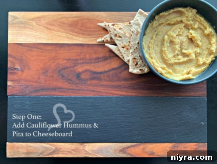 Step one of building a Mediterranean Cheeseboard: placing hummus and pita