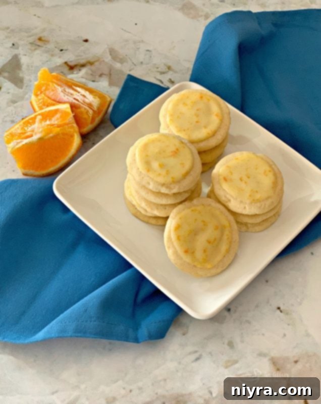 A plate of freshly baked and glazed Orange Meltaway Cookies, vibrant and appealing