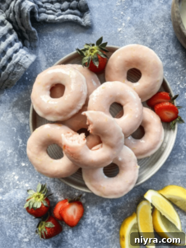 A stack of baked strawberry lemonade donuts on a white plate, highlighting the versatility of a donut pan.