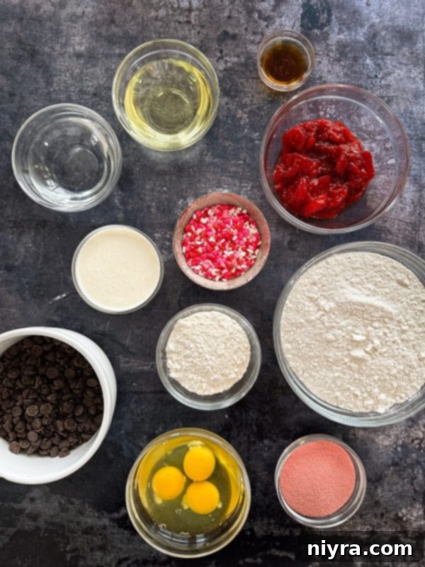 A close-up of a single baked chocolate covered strawberry donut with pink and red sprinkles.