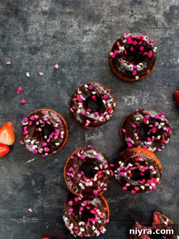 Ingredients for chocolate covered strawberry donuts laid out, including cake mix, Jell-O, strawberries, eggs, oil, water, chocolate chips, and heavy cream.