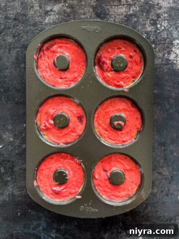 Mixing bowl with strawberry donut batter and strawberries being folded in.