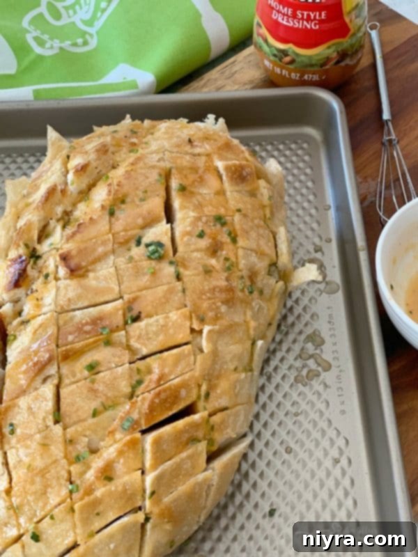 Drizzling melted butter mixture into the cracked sourdough bread using a turkey baster