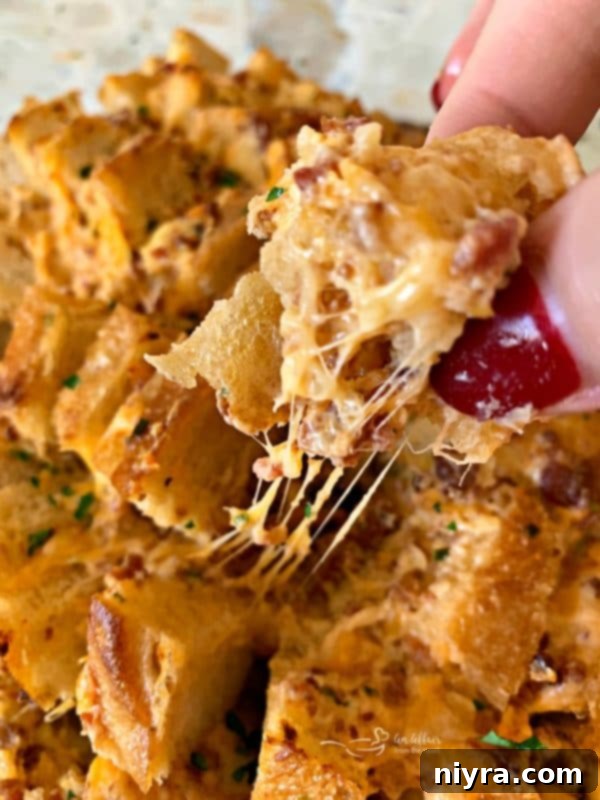 A piece of Dorothy's Cheesy Bacon Pull-Apart Bread being pulled, showcasing the gooey cheese stretch