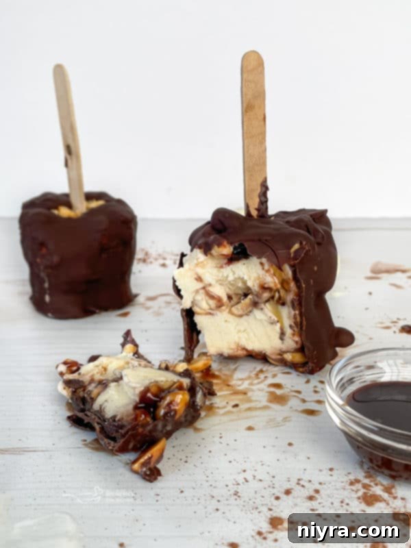 Side angle of two delicious Homemade Buster Bars, showing layers of ice cream, fudge, and peanuts.