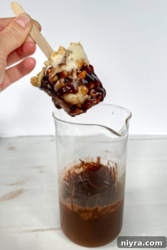 Frozen Buster Bar being dipped into a bowl of melted chocolate.
