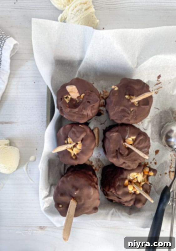 Six freshly dipped Homemade Buster Bars on a baking sheet, ready for the final freeze.