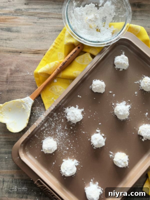 Arranging lemon crinkle cookies evenly on a baking sheet