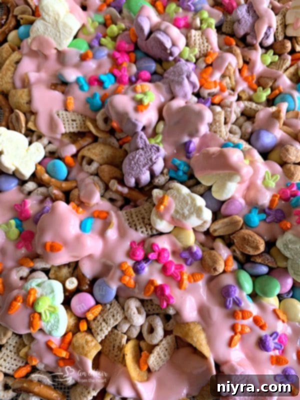 Sweet Springtime Medley 8 Close-up of snack mix ingredients being gently tossed on a parchment-lined baking sheet.