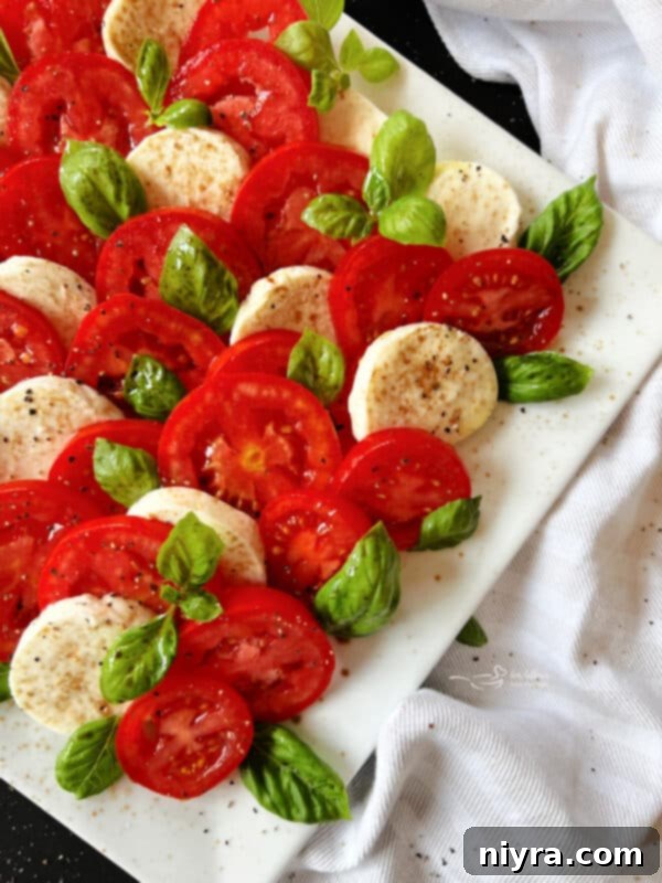 Drizzling olive oil and balsamic glaze over Caprese salad