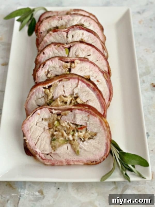 Succulent Bacon Wrapped Pork Loin with Sauerkraut Stuffing on a white platter, ready to be served.