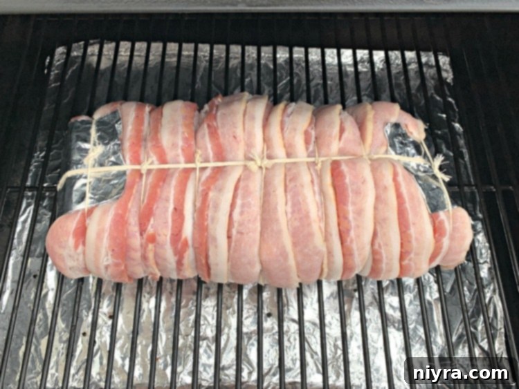 Bacon Wrapped Pork Loin, securely tied and ready to be placed on the smoker grill.