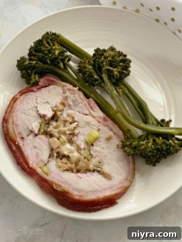 Beautifully sliced Bacon Wrapped Pork Loin with Sauerkraut Stuffing, plated alongside broccolini.